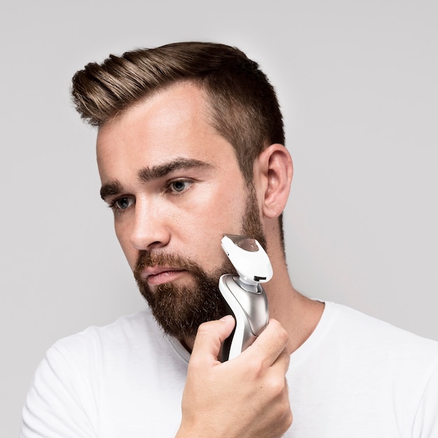 Homem usando barbeador elétrico