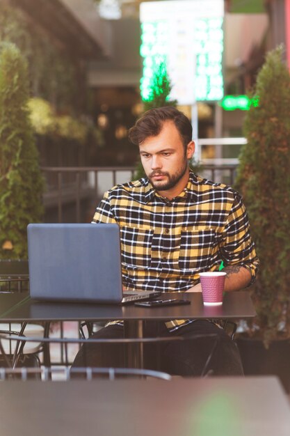 Homem, usando computador portátil, em, loja café