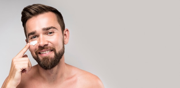 Foto grátis homem usando creme facial com espaço de cópia