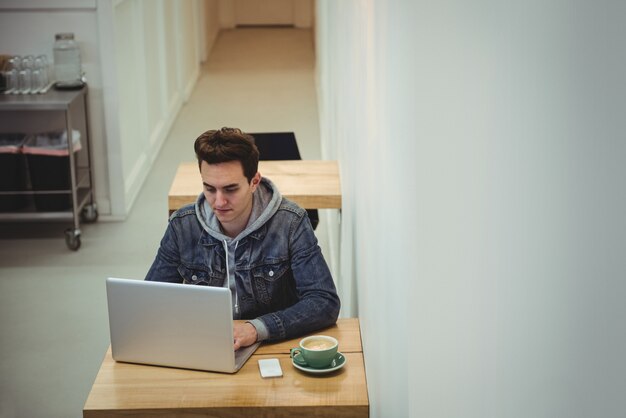 Homem usando laptop em cafeteria