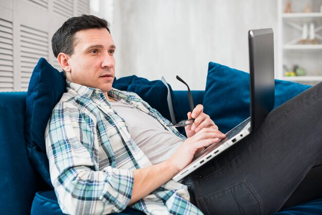 Homem, usando, laptop, ligado, canapé