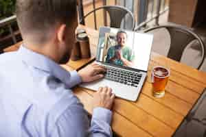 Foto grátis homem usando laptop para videochamada enquanto bebe cerveja