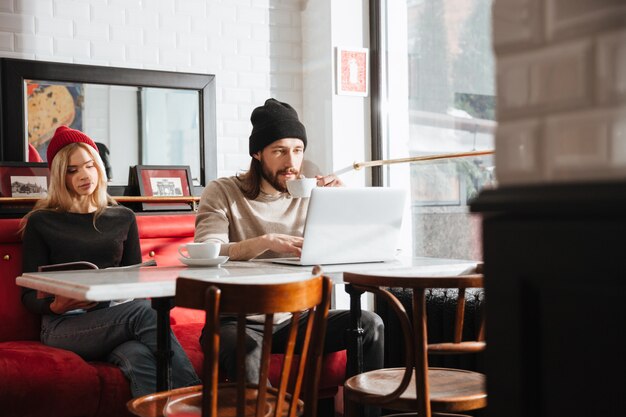 Homem usando laptop perto da namorada no café