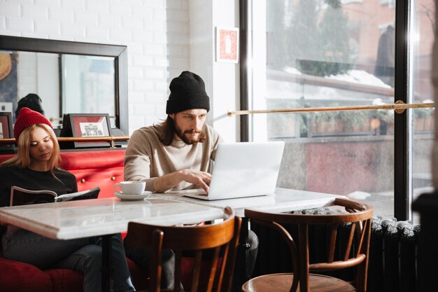 Homem usando laptop perto da namorada