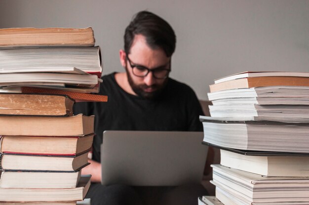 Homem, usando, laptop, perto, livros