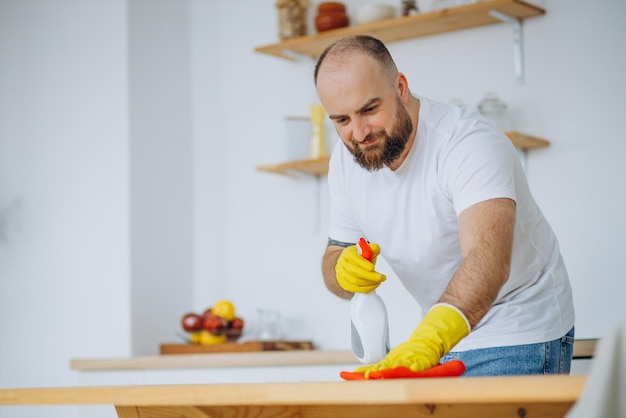 Homem usando luvas de borracha limpando na cozinha