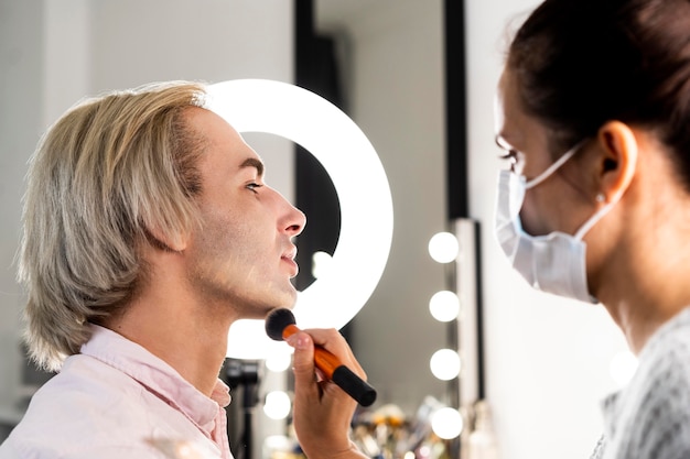 Homem usando maquiagem e vista lateral do salão de beleza