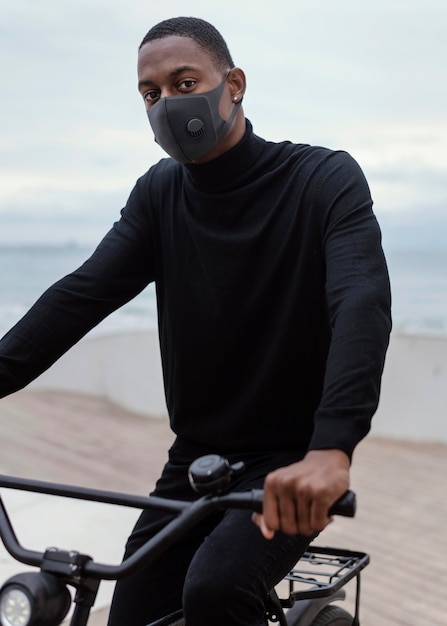 Foto grátis homem usando máscara facial e andando de bicicleta