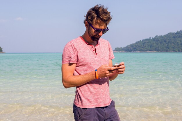 Homem usando telefone celular na praia