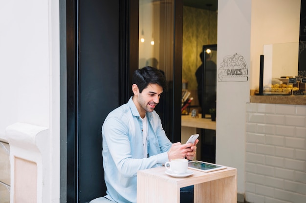 Homem, usando, telefone móvel, em, café