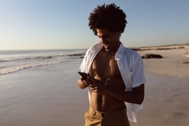 Homem, usando, telefone móvel, praia