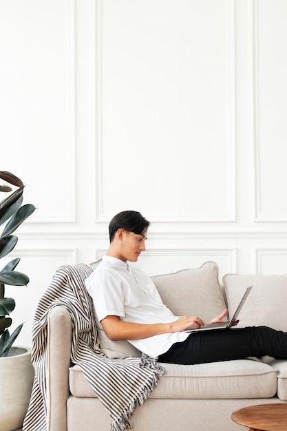 Homem usando um laptop no sofá em uma sala de estar com decoração escandinava