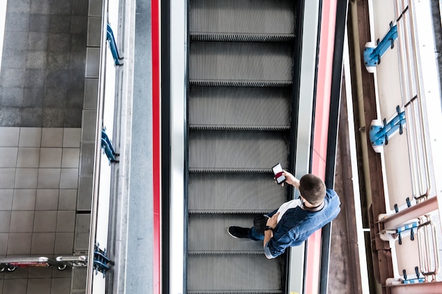 Foto grátis homem, usando, um, smartphone, ligado, a, escada rolante