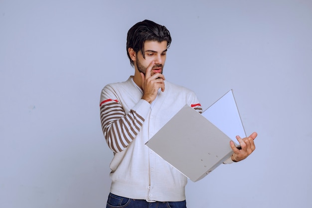 Homem verificando a pasta de relatórios e tentando entender o que está escrito lá.