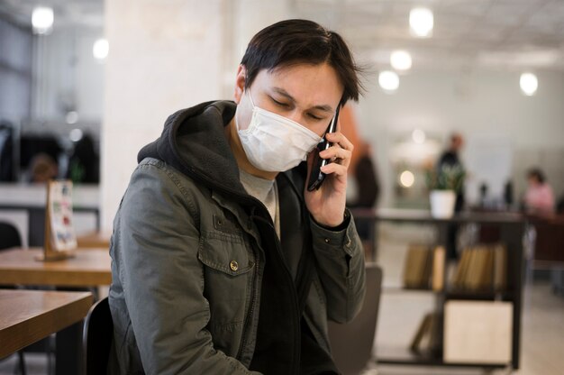 Homem vestindo uma máscara médica e falando ao telefone
