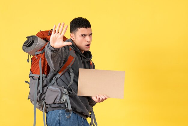 Homem viajante com mochila segurando um papelão e fazendo uma placa de pare