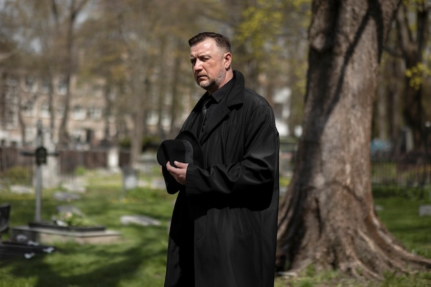 Homem visitando a lápide no cemitério