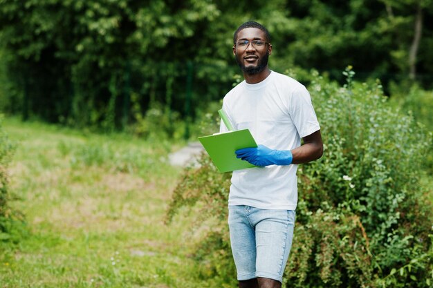 Homem voluntário africano com prancheta no parque África voluntariando pessoas de caridade e conceito de ecologia