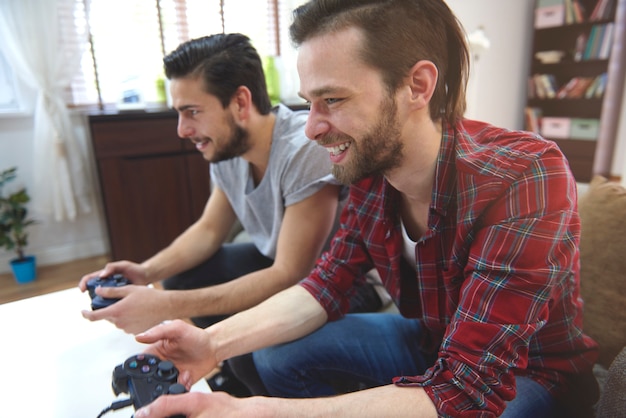 Homens afetuosos jogando playstation na sala de estar