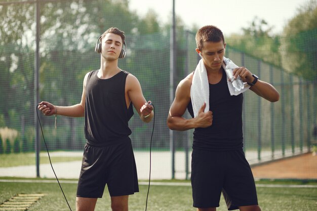 Homens bonitos em uma roupa de esportes em pé em um parque