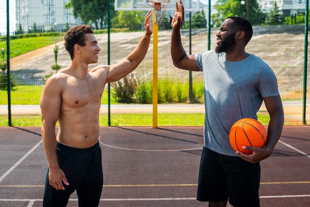 Homens bonitos jogando basquete urbano tiro médio