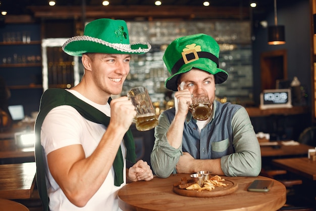 Homens com chapéus verdes. Amigos comemoram o Dia de São Patrício. Celebração em um bar.