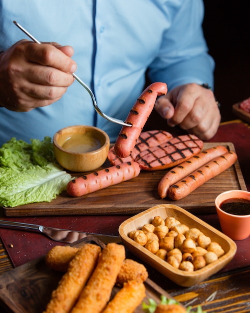 Homens comendo salsichas grelhadas com grão de bico assado e croquetes