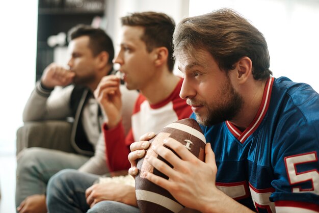 Homens concentrados assistindo jogo de futebol em casa