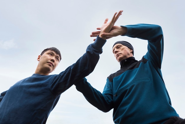 Homens de baixo ângulo praticando tai chi lá fora