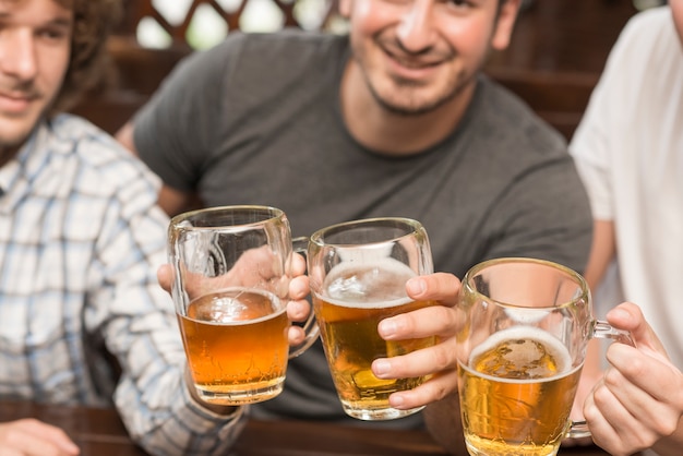 Homens de colheita tinindo canecas em bar