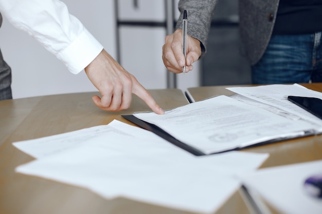 Homens de negócios sentados à mesa dos advogados. Pessoas assinando documentos importantes.