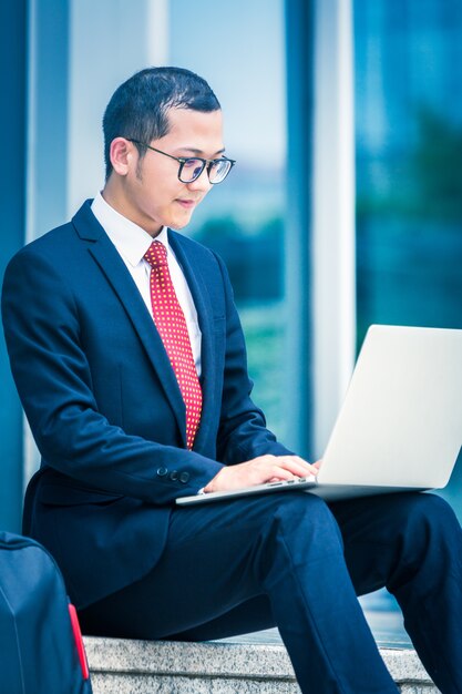 Homens de negócios usam laptops na entrada de um prédio de escritórios