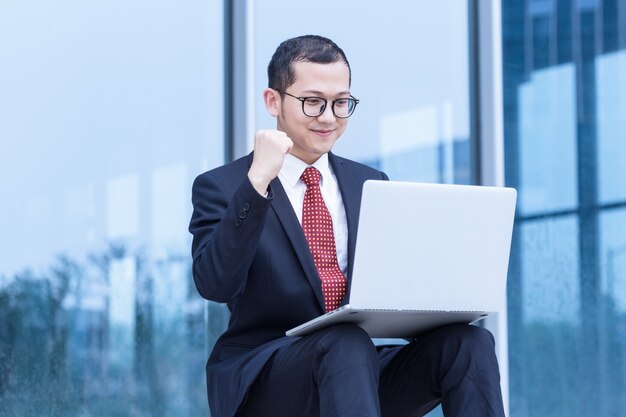 Homens de negócios usam laptops na entrada de um prédio de escritórios