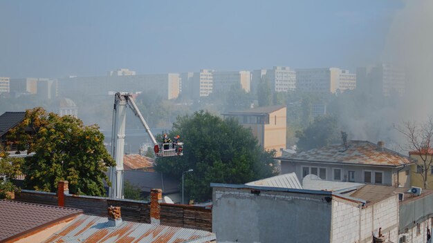 Homens do corpo de bombeiros usando caminhão de bombeiros para ajudar os bombeiros na construção