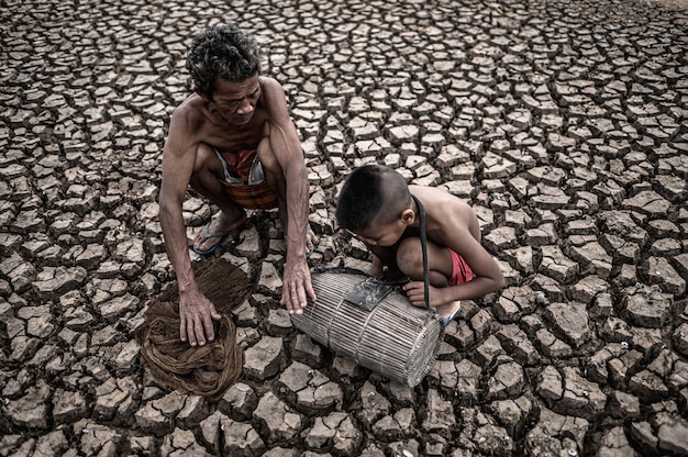 Foto grátis homens e menino idosos encontram peixes em solo seco, aquecimento global