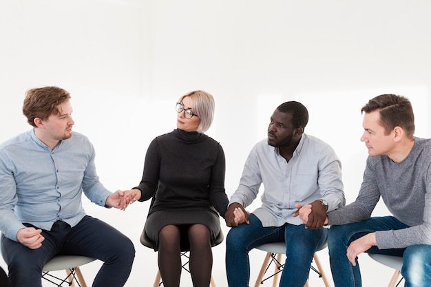 Homens e mulher de mãos dadas na clínica de reabilitação