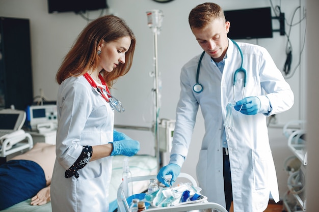 Homens e mulheres em aventais de hospital têm equipamentos médicos nas mãos. A enfermeira insere o medicamento na injeção.