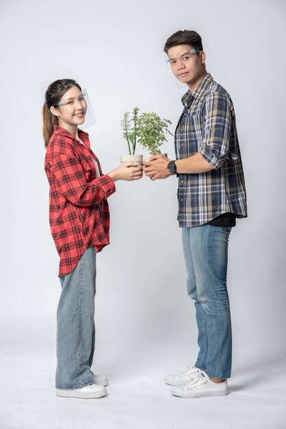 Homens e mulheres em pé e segurando vasos de plantas em casa