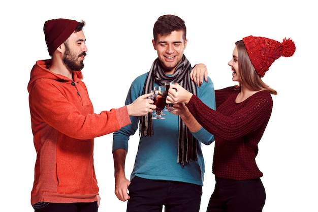 Homens e mulheres europeus sorridentes durante a sessão de fotos da festa. caras posando de amigos no estúdio fest com um copo de vinho com vinho quente quente em primeiro plano.