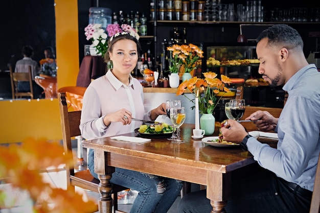 Homens e mulheres negros americanos comendo comida vegana em um restaurante.