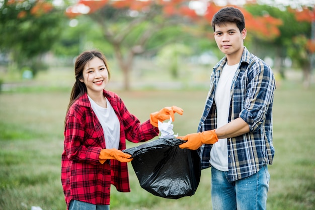 Homens e mulheres se ajudam a coletar lixo.