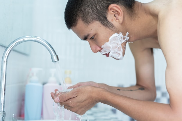 Homens fazem a barba no rosto.