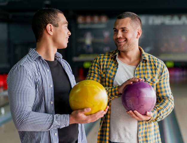 Homens felizes, segurando uma bolas de boliche coloridas