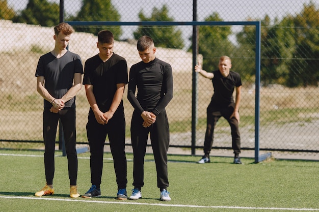 Homens jogam futebol no parque. torneio de mini futebol. cara em um traje esporte preto.