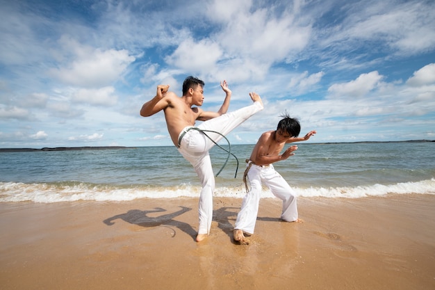 Homens na praia praticando capoeira juntos