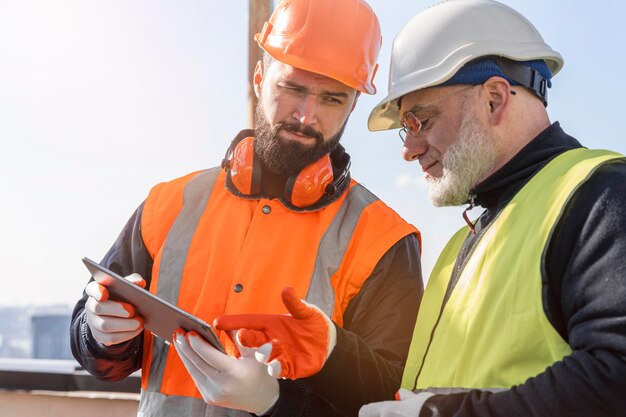 Homens olhando para um tablet, tiro médio