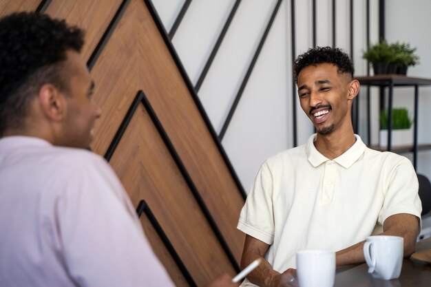 Homens sorridentes de vista lateral conversando no trabalho