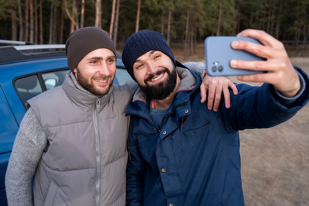 Homens sorridentes em tiro médio tirando selfie