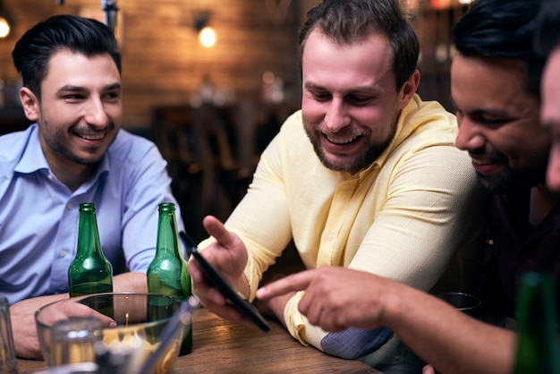 Homens usando telefone celular durante reunião no bar