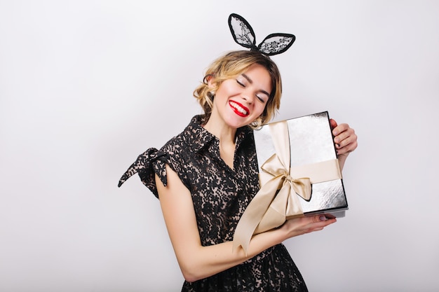 Hora de festa louca de mulheres bonitas em um vestido preto elegante com caixa de presente, comemorando o aniversário, se divertindo, dançando. rosto de emoção, lábios vermelhos, olhos fechados.